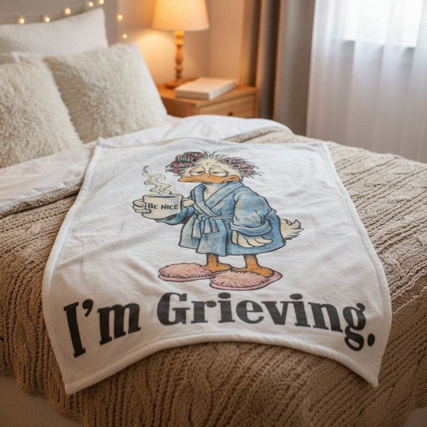 Cartoon character in a bathrobe holding a mug with 'Be Nice' text, with the text 'I'm Grieving' below.